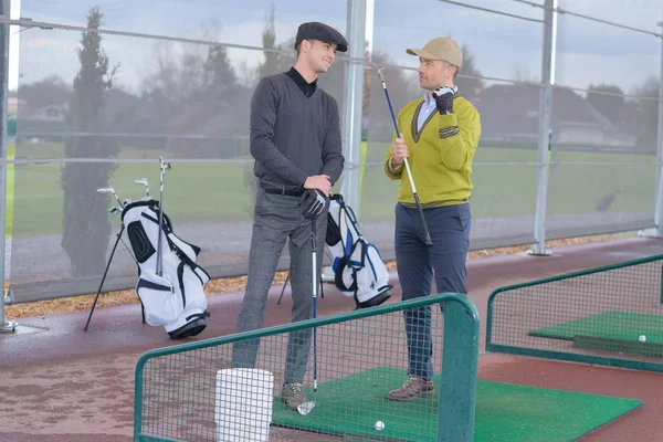 Golfistas homens que se comunicam no stand de treinamento de golfe — Fotografia de Stock