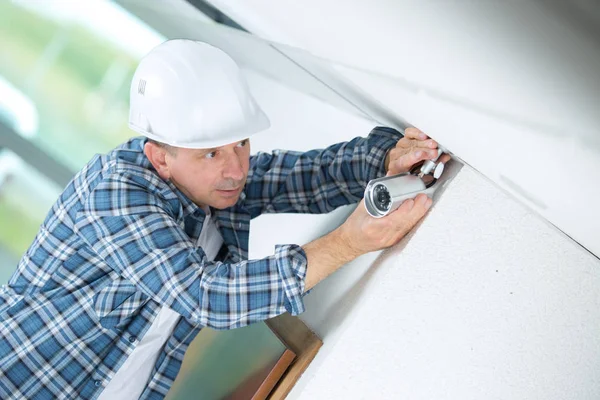 Técnico ajustando câmera cctv na parede — Fotografia de Stock