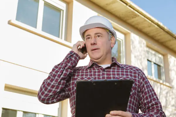 Architect supervising a construction using cell phone outdoors — Stock Photo, Image