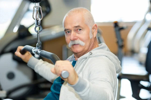 Senior man in sportschool trainen met gewichten — Stockfoto