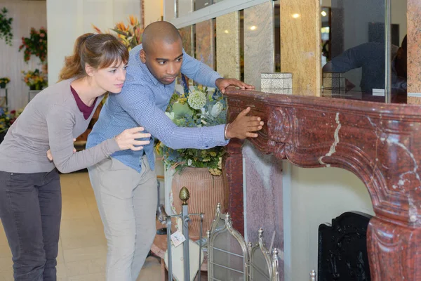 Happy young couple looking at chimney in furniture store — Stock Photo, Image