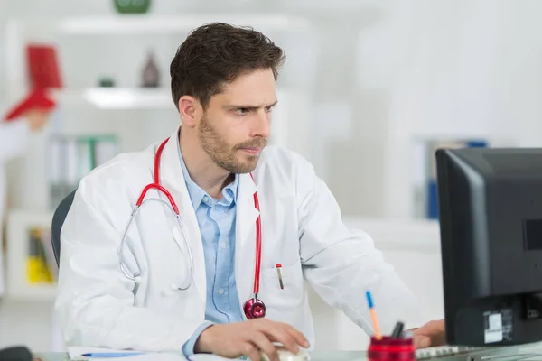 Knappe mannelijke arts werkzaam in office — Stockfoto