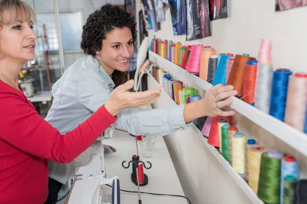 Deux femmes choisissant des bobines de fil dans le magasin de couture — Photo