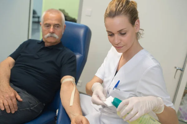 Старший мужчина и медсестра проверяют уровень сахара в крови — стоковое фото