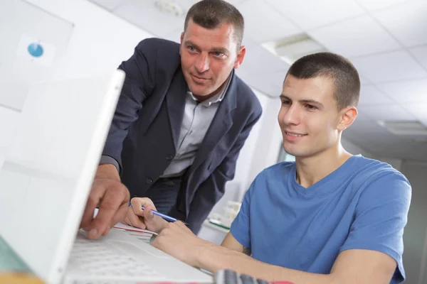 Professor hjälper en elev i klassrummet på högskolan — Stockfoto