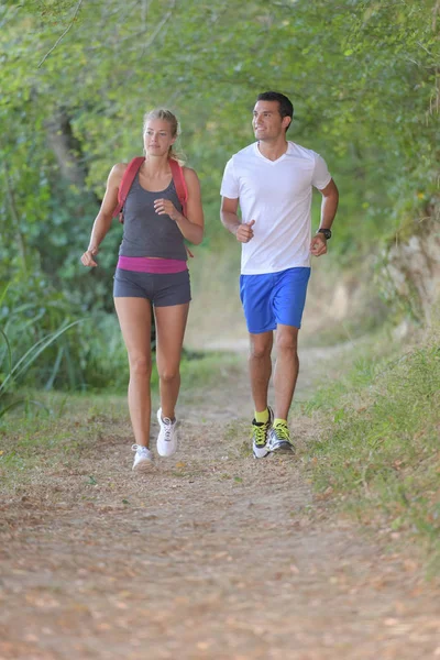 Joven pareja sana corriendo en el bosque — Foto de Stock