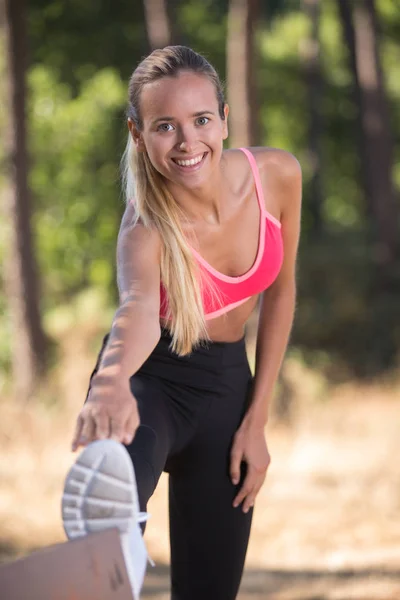 Jonge fitness vrouw loper uitrekkende benen vóór uitvoeren — Stockfoto