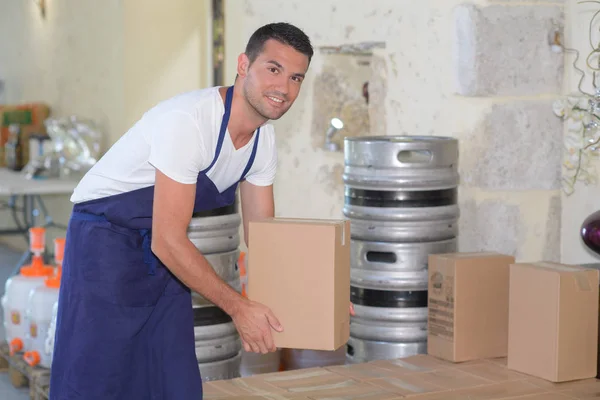 Uomo in cantina sollevamento scatola di cartone — Foto Stock