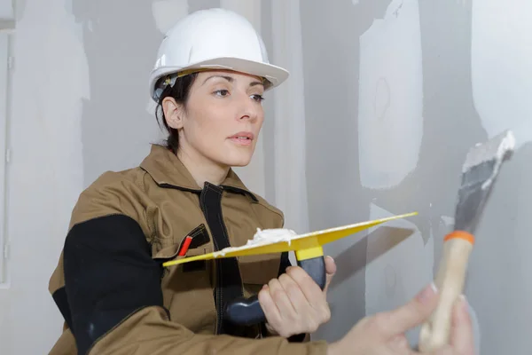 Constructor mujer interior trabajador yeso pared con paleta de espátula herramienta — Foto de Stock