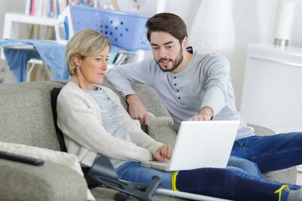 Young man helping injured woman on computer — Stock Photo, Image