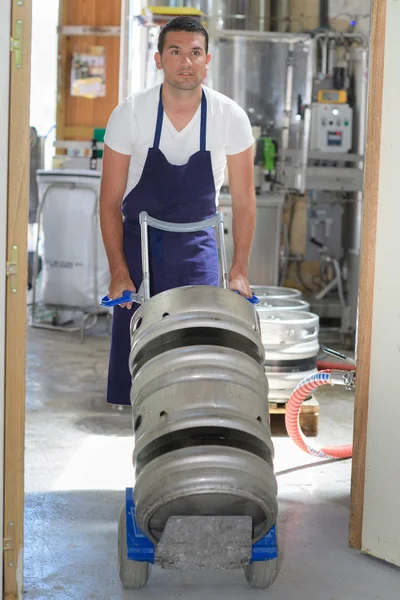Trabajador que lleva barril con cerveza en la cervecería — Foto de Stock