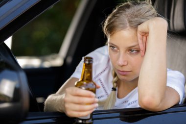 drunk woman driving and holding beer bottle inside a car clipart