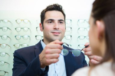 attractive optician assisting female testing new glasses clipart