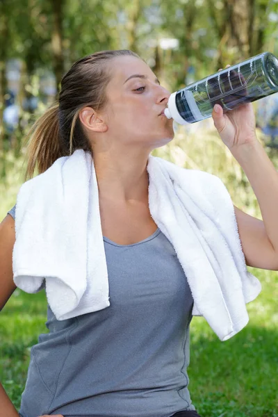 Woman drinking water in between exercise — ストック写真