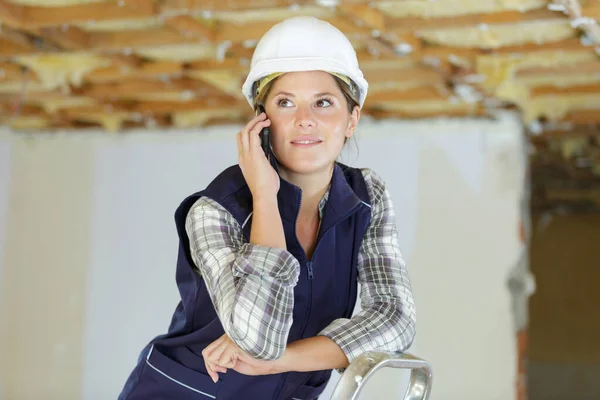 Woman builder with using smart phone — ストック写真