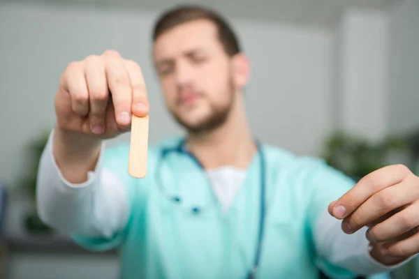 Erkek doktor hastaların boğazına bakmak için çubuk tutuyor. — Stok fotoğraf