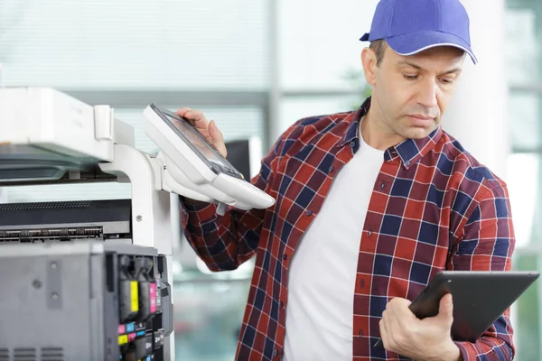 Technicus die een tablet gebruikt om een printer te repareren — Stockfoto