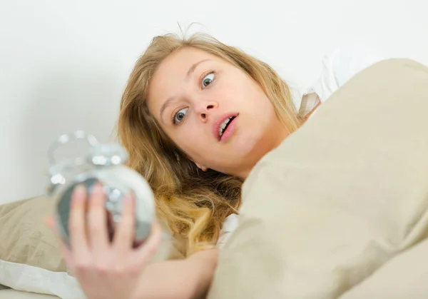 Mulher na cama olhando em choque em seu despertador — Fotografia de Stock