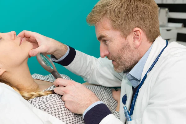 Geconcentreerde dermatoloog met behulp van medische loupe in de kliniek — Stockfoto