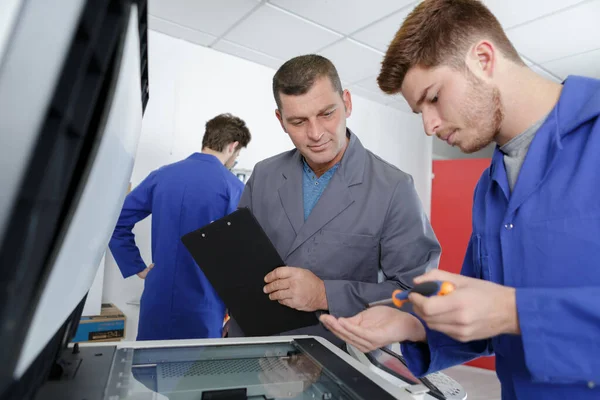 Aprendiz do sexo masculino que fixa um supervisor de impressora assistindo — Fotografia de Stock