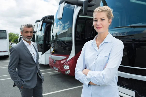 Улыбающаяся деловая женщина и бизнесмен снаружи автобуса — стоковое фото