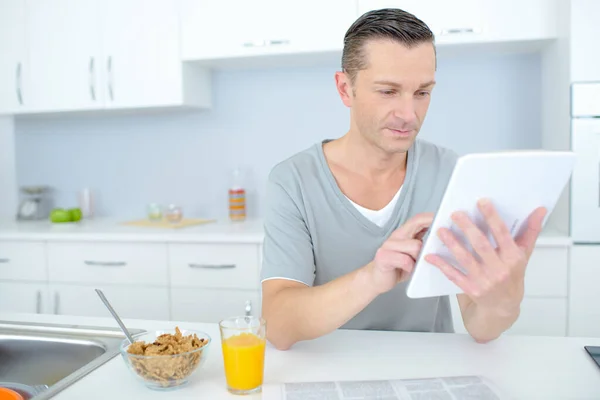 Mann liest während des Frühstücks in Küche Nachrichten in Tablet — Stockfoto