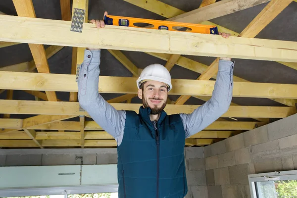 Constructeur masculin avec niveau sur une maison à ossature en bois — Photo