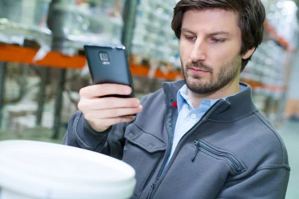 Αρσενικό πωλητή ελέγχει ένα τηλέφωνο για τον τύπο της μπογιάς — Φωτογραφία Αρχείου