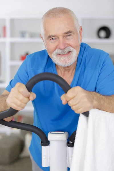 Senior man working exercise on bike indoors — ストック写真