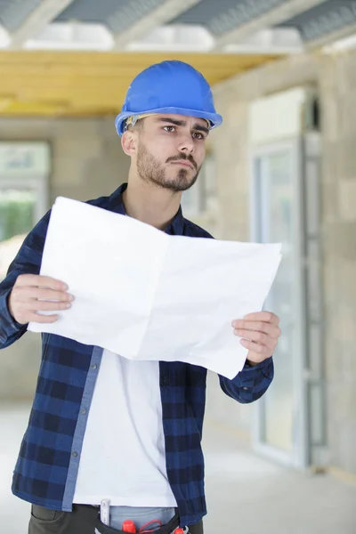 Perplesso giovane costruttore tuttofare sala d'esame e ristrutturazione pianificazione — Foto Stock