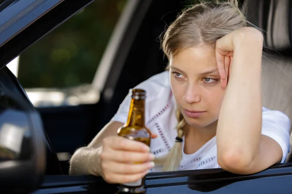 Mulher bêbada dirigindo e segurando garrafa de cerveja dentro de um carro — Fotografia de Stock