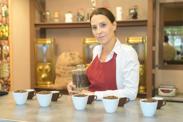 Mulher no café pela exposição de grãos de café de variedade diferente — Fotografia de Stock