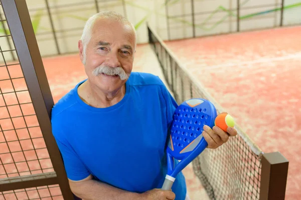 Glad senior manlig tennisspelare inomhus — Stockfoto