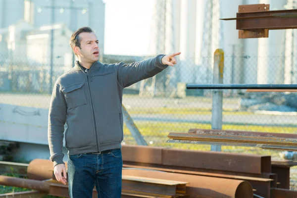 Man in industrial yard pointing into distance and shouting out — Stock Photo, Image