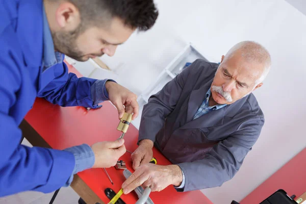 Zwei Handwerker montieren Ersatzschlossmechanismus in Innentür — Stockfoto