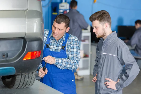 Mekanikern byta däck av bil i garage — Stockfoto