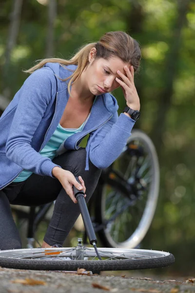 ผู้หญิงไม่มีปัญหาในการพองยางจักรยาน รูปภาพสต็อก