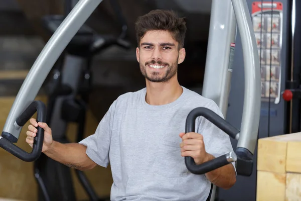 Porträtt av ung man med hjälp av gym utrustning — Stockfoto