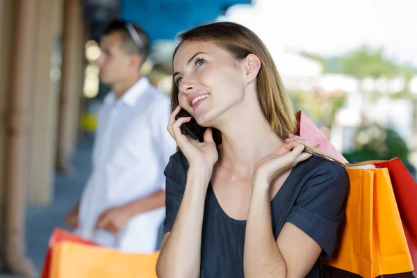 Junge lächelnde Frau mit Einkaufstaschen und Smartphone — Stockfoto