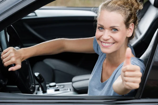 Cute woman giving thumb up inside her car — ストック写真