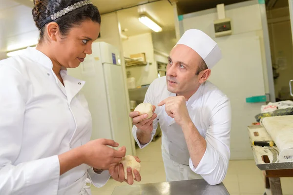 젊은 여자 견습공을 훈련시키는 장성 한 남자 요리사 — 스톡 사진