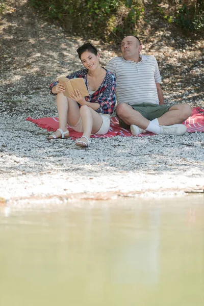 Pareja relajándose en embarcadero al lado del lago — Foto de Stock