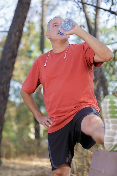 Middle-age running man drinking water — Stockfoto