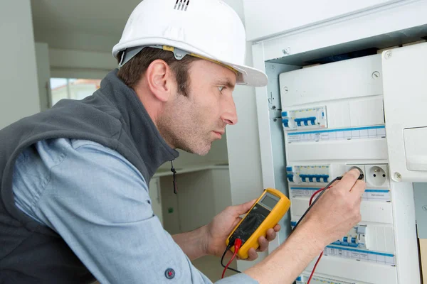 Mannelijke technicus met multimeter in fusebox — Stockfoto