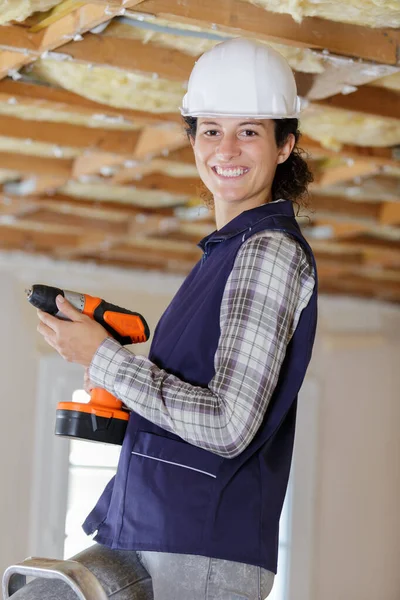 Vrouwelijke bouwer met behulp van een boor — Stockfoto