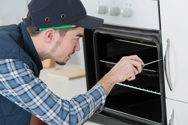 Młody mechanik w ogólnej instalacja zupełnie nowy Piec w kuchni — Zdjęcie stockowe