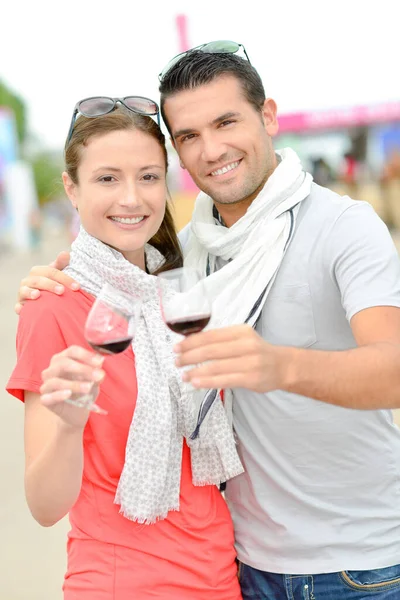 Casal fazendo um brinde com copos de vinho tinto — Fotografia de Stock