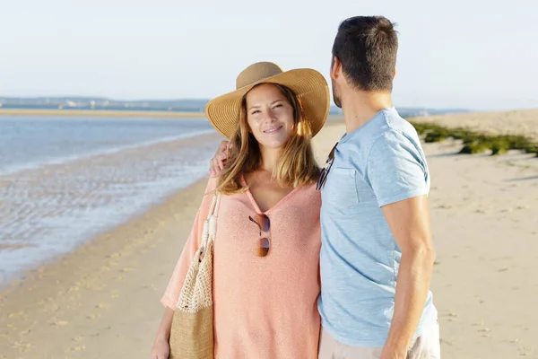 Пара прогуливаясь по пляжу человек оглядываясь назад через плечо — стоковое фото