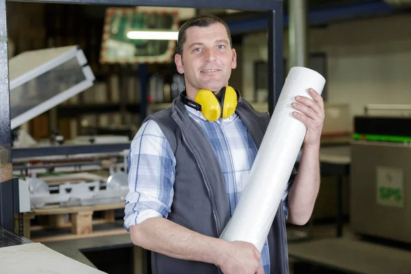 A csomagolásgyártásban nagy papírtekercset tartó munkavállaló — Stock Fotó