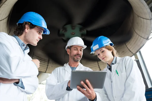 Ingenieros de hombres y mujeres que utilizan tabletas para monitorear la fábrica — Foto de Stock